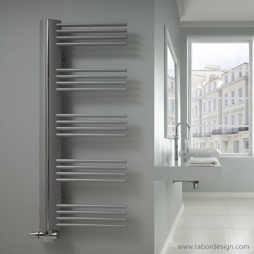 Grzejniki dekoracyjne premium. Asymetryczny srebrny grzejnik drabinkowy w nowoczesnym jasnym pomieszczeniu.